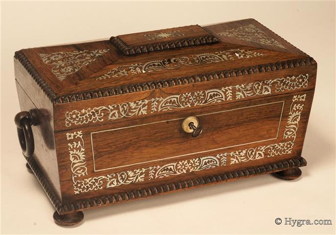 Tea chest in highly figured rosewood of architectural form by R Dalton of the Bazaar, Soho Square. The chest  is finely inlaid with mother of pearl which depicts stylized flora ; the chest  is standing on turned rosewood feet having turned drop handles. Inside the tea chest there are two liftout hinged canisters (retaining most of their original leading) and a particularly fine cut lead crystal bowl. Circa 1835  Enlarge Picture